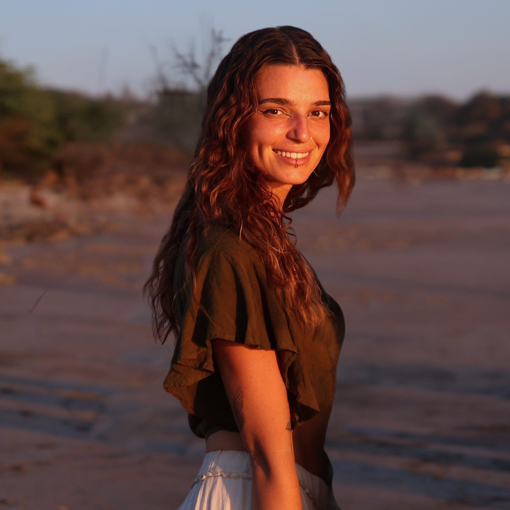 Woman standing in a natural setting with warm lighting