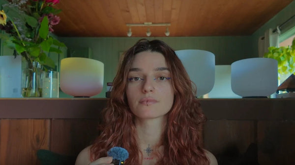 Jade holding a mallet in front of colorful crystal singing bowls